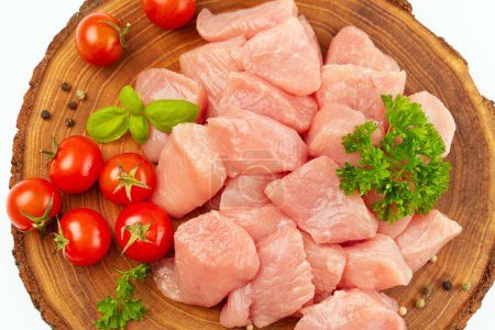 Frische Stücke von Putenfleisch.Rohe Hühner.Rohe Stücke von Putenfleisch mit Gemüse und Tomaten auf einem Holzbrett vor weißem Hintergrund .Ogranic Nahrung und gesundes Ess.Hühnerfilet.Nahaufnahme.