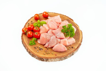 Fresh pieces of turkey meat.Raw chicken.Raw pieces of turkey meat with greens and tomatoes on a wooden board against a white background.Ogranic food and healthy eating.chicken fillet.