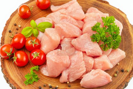 Fresh pieces of turkey meat.Raw chicken.Raw pieces of turkey meat with greens and tomatoes on a wooden board against a white background.Ogranic food and healthy eating.chicken fillet.Close up.