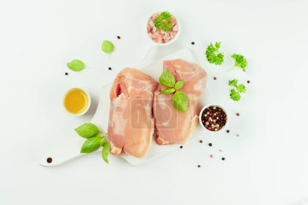 Raw fresh skinless chicken thigh meat with fresh herbs on a white background.Copy space.Food for retail.Ogranic food,healthy eating.Food concept.Top view.