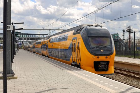 Foto de VIRM trenes interurbanos de NS corre a lo largo de la plataforma en la estación Lage Zwaluwe en los Países Bajos - Imagen libre de derechos