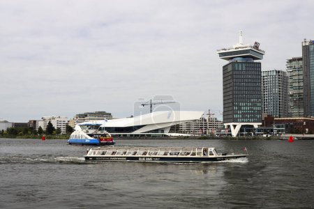 Foto de EYE Film Instituut (instalación cinematográfica) Amsterdam en el agua IJ con ferry y barco turístico en los Países Bajos - Imagen libre de derechos