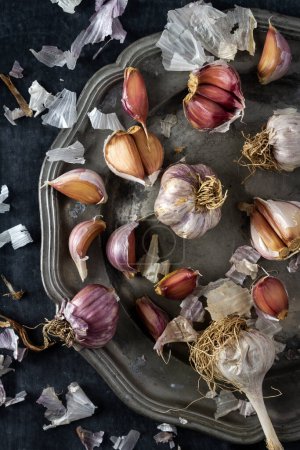 Raw garlic on grey pewter plate. Flat lay. Top view. Food concept. Dark mood food photography.