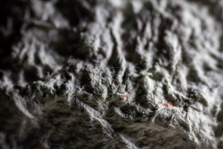 Extreme close up of old gray handmade paper mache with a structure and rough texture. Paper recycling. Selective focus, shallow depth of field.