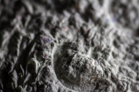 Extreme close up of old gray handmade paper mache with a structure and rough texture. Paper recycling. Selective focus, shallow depth of field.