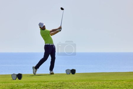 Foto de Golfista en un campo de golf, listo para partir. Golfista con palo de golf golpeando la pelota para el tiro perfecto. - Imagen libre de derechos