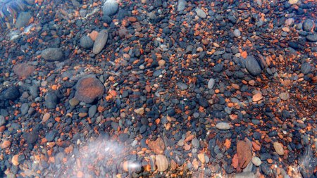 Téléchargez les photos : Détail de pavés dans l'eau transparente de la célèbre plage rouge de Santorin. Contexte, pierre naturelle, texture. - en image libre de droit