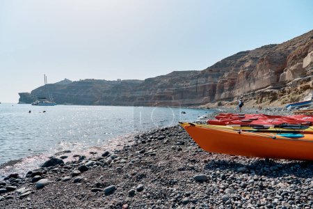 Des kayaks colorés se trouvent en rangée sur la plage de sable noir (plage de Mesa Pigadia). Îles Grecques, Santorin, Vacances en Europe