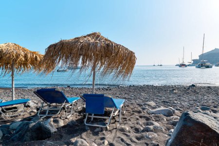 Vista con playa y botes en la playa de arena negra de Akrotiri que se conoce localmente como Playa Mesa Pigadia. Islas griegas, Santorini, Vacaciones europeas