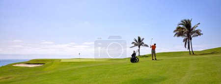 Golfer auf einem Golfplatz, in der Nähe der Flagge auf dem Grün. Golfer mit Golfschläger schlägt den Ball für den perfekten Schlag.