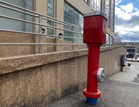 Téléchargez les photos : Une bouche d'incendie rouge se dresse sur l'asphalte près d'un bâtiment dans la ville allemande de Pforzheim. Gros plan. Gorizontal photo. - en image libre de droit