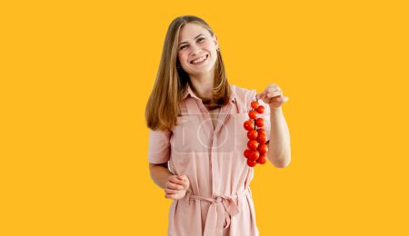 Photo for Woman is holding tomatoes. Healthy food. Vegans. Vegetarian. Bunch of tomatoes. Isolated over bright yellow color background. - Royalty Free Image