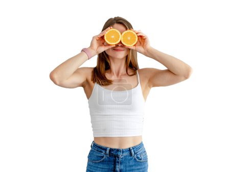 Foto de Young charming woman holding two halves of oranges near her beautiful face on white background. Healthy food concept. - Imagen libre de derechos