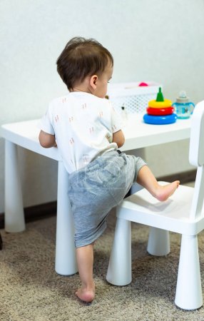 Téléchargez les photos : Un petit garçon assis à une table blanche - en image libre de droit