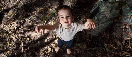 Téléchargez les photos : Jeune garçon debout dans un champ boueux. Un petit garçon qui se tient dans la terre - en image libre de droit