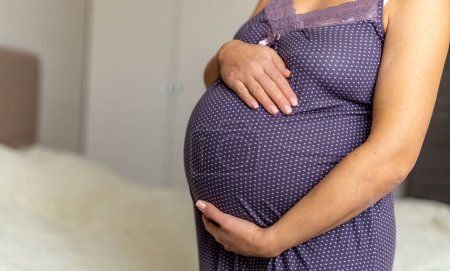 A pregnant woman wearing a purple polka dot dress