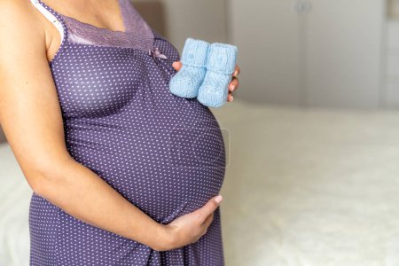 Foto de Una mujer embarazada sosteniendo un par de zapatos azules - Imagen libre de derechos