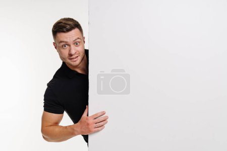 A man peeking out from behind a white panel