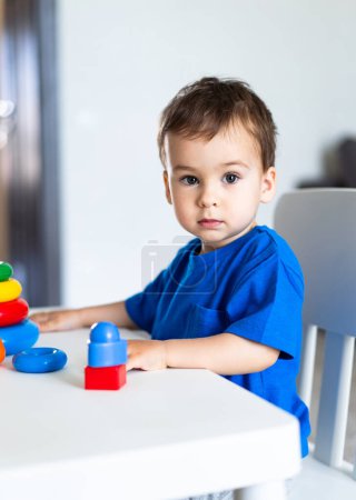 Ein kleiner Junge sitzt an einem Tisch mit einem Stapel Spielzeug