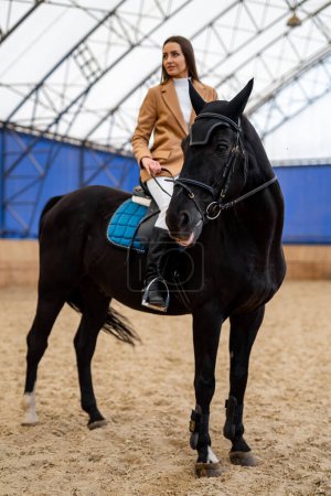 Eine Frau reitet auf dem Rücken eines schwarzen Pferdes