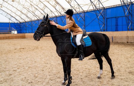 Téléchargez les photos : Femme chevauchant un cheval dans une arène. Une femme montée sur un majestueux cheval noir - en image libre de droit