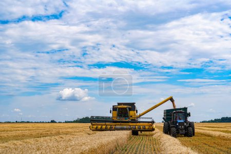 Téléchargez les photos : Centrale agricole dans un Golden Expanse. Un tracteur et une remorque tracteur dans un champ de blé - en image libre de droit