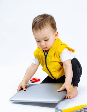 Téléchargez les photos : A Curious Toddler Exploring the Digital World. Un petit enfant jouant avec un ordinateur portable - en image libre de droit