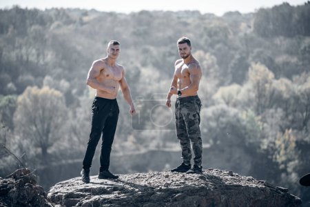 Téléchargez les photos : Deux hommes debout sur un gros rocher. Deux hommes aventureux conquirent un sommet majestueux - en image libre de droit