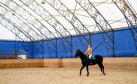 Photo for A person riding a horse inside of a building. A Person Riding a Horse Inside a Majestic, Historic Building - Royalty Free Image