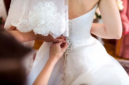 Téléchargez les photos : Une mariée se prépare pour son jour spécial, une mariée met sa robe de mariée - en image libre de droit