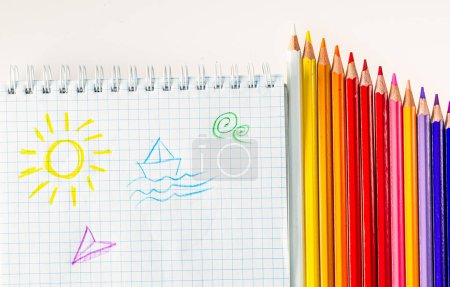Téléchargez les photos : Un réseau coloré de crayons donnant vie à un soleil et à un bateau artistiques. Une rangée de crayons de couleur à côté d'un dessin d'un soleil et d'un bateau - en image libre de droit