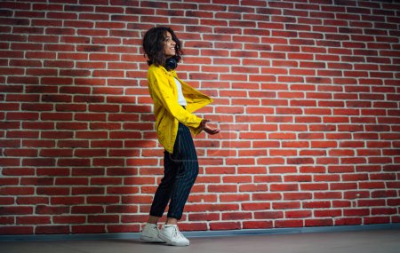 Foto de Una mujer de pie frente a una pared de ladrillo. La fuerza serena de una mujer contra la belleza intemporal de una pared de ladrillo - Imagen libre de derechos