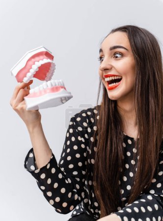 Téléchargez les photos : Une femme tenant un modèle de dent. Une femme affichant fièrement un modèle dentaire précis d'une dent - en image libre de droit