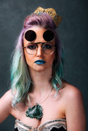 Téléchargez les photos : Une femme aux cheveux bleus et verts portant des lunettes. Le visionnaire vibrant : une femme aux lunettes à bascule aux cheveux bleus et verts - en image libre de droit