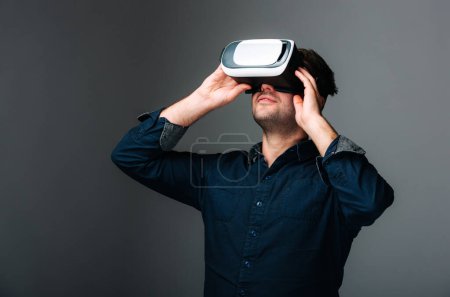 Téléchargez les photos : Un homme tenant un dispositif virtuel sur son visage. Réalité virtuelle : La technologie immersive prend le monde d'assaut - en image libre de droit