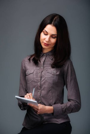 Photo for An Organized Woman Capturing Thoughts on Her Trusty Clipboard. A woman holding a clipboard and writing on it - Royalty Free Image