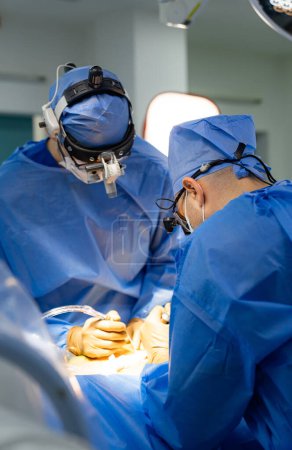 Téléchargez les photos : Deux chirurgiens opérant dans une salle d'opération. Deux chirurgiens pratiquant la neurochirurgie dans une salle d'opération moderne - en image libre de droit