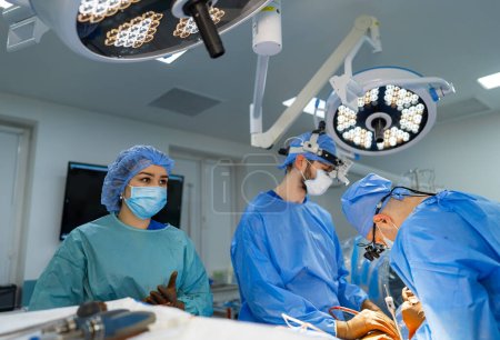 Téléchargez les photos : Un groupe de chirurgiens dans une salle d'opération. Une équipe de chirurgiens effectuant une neurochirurgie dans une salle d'opération moderne - en image libre de droit