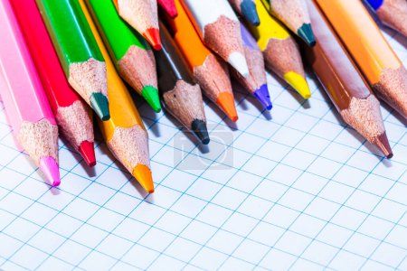 Téléchargez les photos : Une rangée de crayons de couleur assis sur un morceau de papier. Un arc-en-ciel de crayons de couleur sur une toile blanche - en image libre de droit