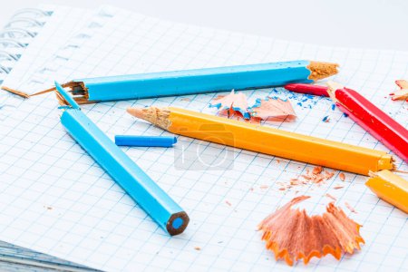 Téléchargez les photos : Un tas de crayons et de crayons assis sur un morceau de papier. Un tableau coloré de crayons et de crayons sur une feuille blanche - en image libre de droit