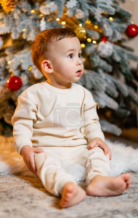 Photo for A baby sitting in front of a christmas tree. A Baby Sitting in Front of a Christmas Tree - Royalty Free Image