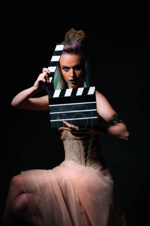 Photo for A woman in a dress holding a clap board. A Stylish Woman Holding a Clapboard - Royalty Free Image