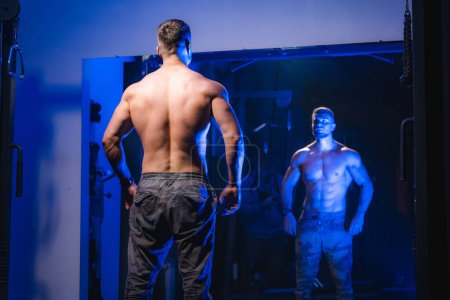 Foto de Un reflejo de sí mismo. Un hombre parado frente a un espejo con la espalda a la cámara - Imagen libre de derechos