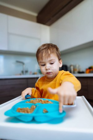 Téléchargez les photos : L'aventure culinaire d'un jeune gourmet, un petit garçon fait l'expérience de la magie de la nourriture à sa table - en image libre de droit