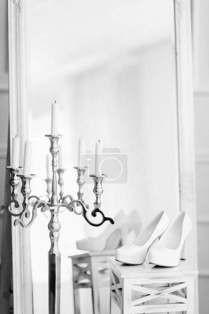 A stunningly artistic composition featuring a pair of high heels gracefully placed on a table in proximity to a mirror, creating an alluring reflection.