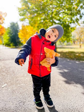 Foto de Young Boy Holding Stuffed Animal. Un niño sostiene un animal de peluche firmemente en sus brazos, mostrando su afecto hacia el juguete. - Imagen libre de derechos
