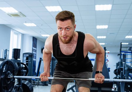 Téléchargez les photos : Homme accroupi sur Barbell dans la salle de gym, exercice de musculation pour la construction des muscles du bas du corps - en image libre de droit