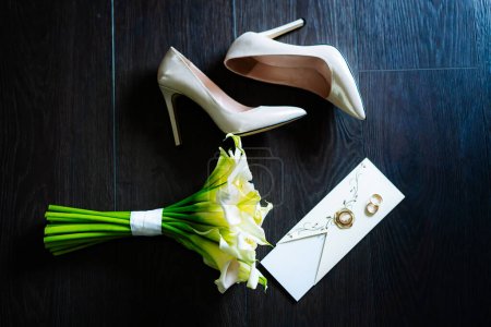 Photo for Bouquet of Flowers and Shoes on Table. A photo of a bouquet of flowers and a pair of shoes placed on a table. - Royalty Free Image