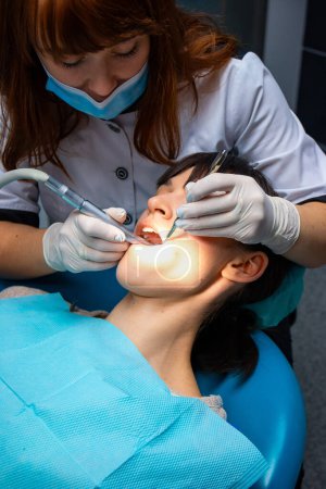 Foto de Mujer sometida a chequeo dental por dentista. Una mujer que recibe tratamiento dental se somete a una revisión dental exhaustiva por su dentista. - Imagen libre de derechos