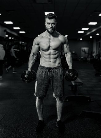 Foto de Hombre musculoso entrena en el gimnasio. El atleta realiza ejercicios con pesas. - Imagen libre de derechos